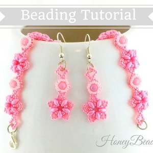 以下が含まれることがあります： ピンクのビーズでできたブレスレットとイヤリングのセット。花柄のデザイン。イヤリングはシルバーのフックでぶら下がっている。ブレスレットはシルバーの留め具。セットには「Honey Beads1」のラベルが付いている。