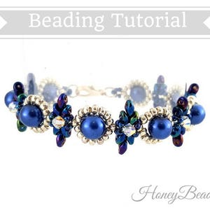 以下が含まれることがあります： 銀色の留め具が付いたビーズブレスレット。青い虹色のビーズが花柄に並んでいます。ブレスレットは白い背景に置かれており、"Beading Tutorial"と"HoneyBeads1"の文字が見えます。