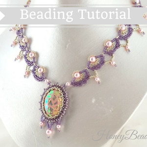 以下が含まれることがあります： 紫と金のデザインのビーズネックレスで、大きな虹色の楕円形のペンダントが付いています。ネックレスは繊細で複雑なパターンで、ピンクのビーズが特徴です。画像の上部には「Beading Tutorial」というテキストがあります。画像の下部には「Honey Beads」というテキストがあります。