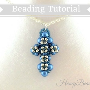 以下が含まれることがあります： 青と銀色のビーズでできたクロス型のペンダントネックレス。クロスは小さな丸いビーズで作られており、繊細で複雑なデザインです。ネックレスは銀色のチェーンに付いています。