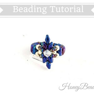 以下が含まれることがあります： 中央にクリスタルを配した、青、紫、金色のデザインのビーズリング。リングは花のような形で、白い背景に配置されています。「Beading Tutorial」の文字が上部にあります。