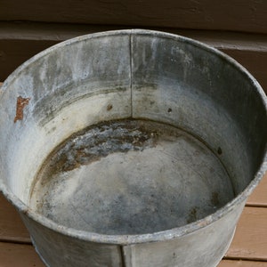 May include: A large, round, galvanised metal tub with a slightly rusted interior. The tub is empty and appears to be vintage.