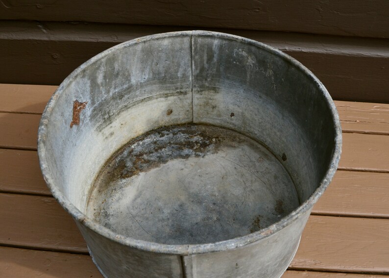 May include: A large, round, galvanised metal tub with a slightly rusted interior. The tub is empty and appears to be vintage.