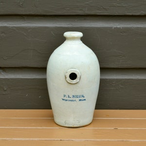 May include: White ceramic bottle with a blue inscription that reads "P.L. Rider, Worcester, Mass."