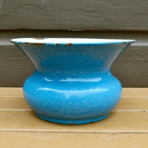 May include: A vintage blue enamel pitcher with white speckles. The pitcher has a wide mouth and a rounded body.