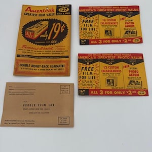 May include: Vintage film packaging and promotional materials. Includes a film box, promotional cards offering free film and enlargements, and an envelope addressed to a film lab. The film box is black and white, with the text "America's Greatest Film Value."