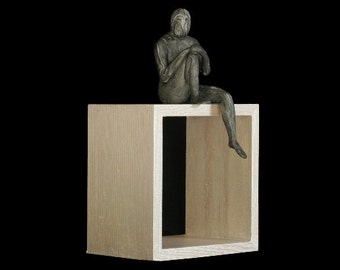 She Was Taught to Think Outside the Box is a O.O.A.K(one of a kind) small sculpture of a nude female sitting on top of a wooden box.