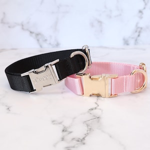 May include: Two dog collars, one black with a silver buckle and the word "Puppy" engraved on it, and one pink with a gold buckle.