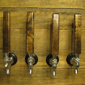 May include: Four wooden beer tap handles with chrome spouts mounted on a wooden wall.