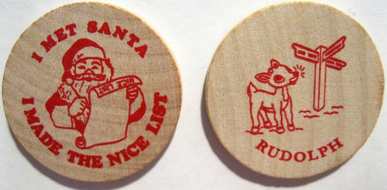 Puede incluir: Dos fichas redondas de madera con texto rojo e ilustraciones. La primera ficha presenta a un Pap&aacute; Noel de dibujos animados sosteniendo un rollo que dice "Nice List" y el texto "I Met Santa I Made The Nice List". La segunda ficha presenta a un reno de dibujos animados con un poste indicador y el texto "Rudolph".