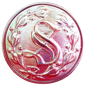 May include: A red and gold metal button with a raised letter "S" surrounded by a wreath of leaves.