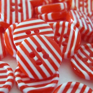 May include: A collection of red and white striped buttons with two holes each. The buttons are made of plastic and have a glossy finish.
