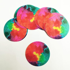 May include: A collection of colorful, round coasters with a vibrant, abstract design. The coasters feature a pattern of red, pink, yellow, and green hues, creating a visually striking and artistic appearance. These coasters are ideal for protecting surfaces.