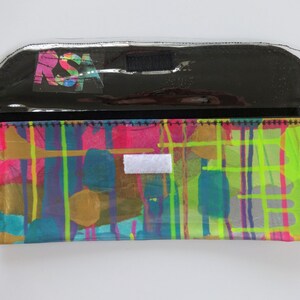 May include: A black and clear plastic pouch with a colorful abstract design and the letters "RSA" printed on the front.