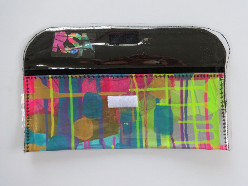 May include: A black and clear plastic pouch with a colorful abstract design and the letters "RSA" printed on the front.