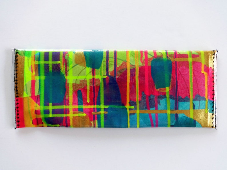 May include: A colorful clutch purse with a gold background and abstract design featuring bright pink, yellow, green, and blue paint splatters.