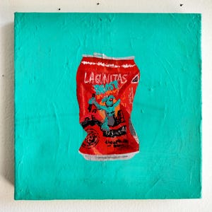 May include: A painting of a crushed red Lagunitas beer can on a teal background. The can features a cartoon character and the brand name. The artwork is mounted on a square canvas, and the background has a textured appearance.