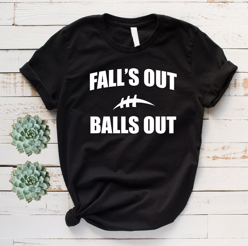 Puede incluir: Camiseta negra con texto blanco que dice "Fall's Out Balls Out" con un gr&aacute;fico de f&uacute;tbol.