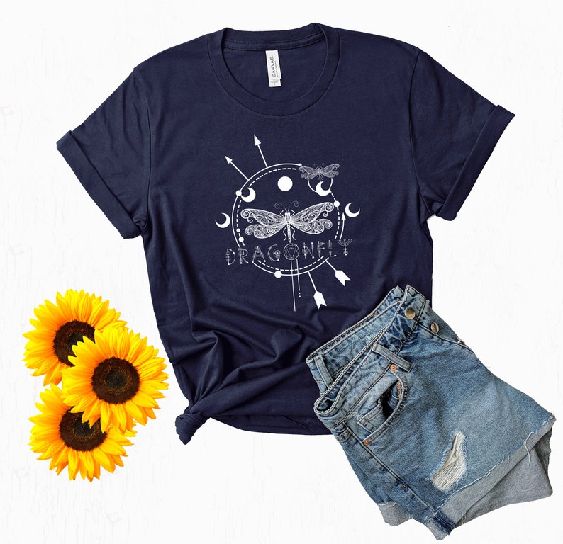 May include: A navy blue t-shirt with a white graphic of a dragonfly with a circle around it and the word "DRAGONFLY" underneath. The graphic also includes moons and arrows.