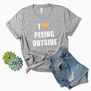 May include: Gray t-shirt with a white heart and the text "I &hearts; Peeing Outside" printed on the front.