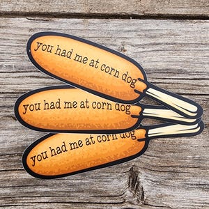 Könnte beinhalten: Drei gelbe Corn Dog-Aufkleber mit dem Text "you had me at corn dog" auf jedem.