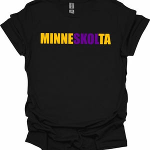 Op de afbeelding: Zwart T-shirt met de tekst "MINNESKOLTA" in gele en paarse letters.