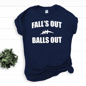 Puede incluir: Camiseta azul marino con texto blanco que dice "Fall's Out Balls Out" y un gr&aacute;fico de f&uacute;tbol blanco.