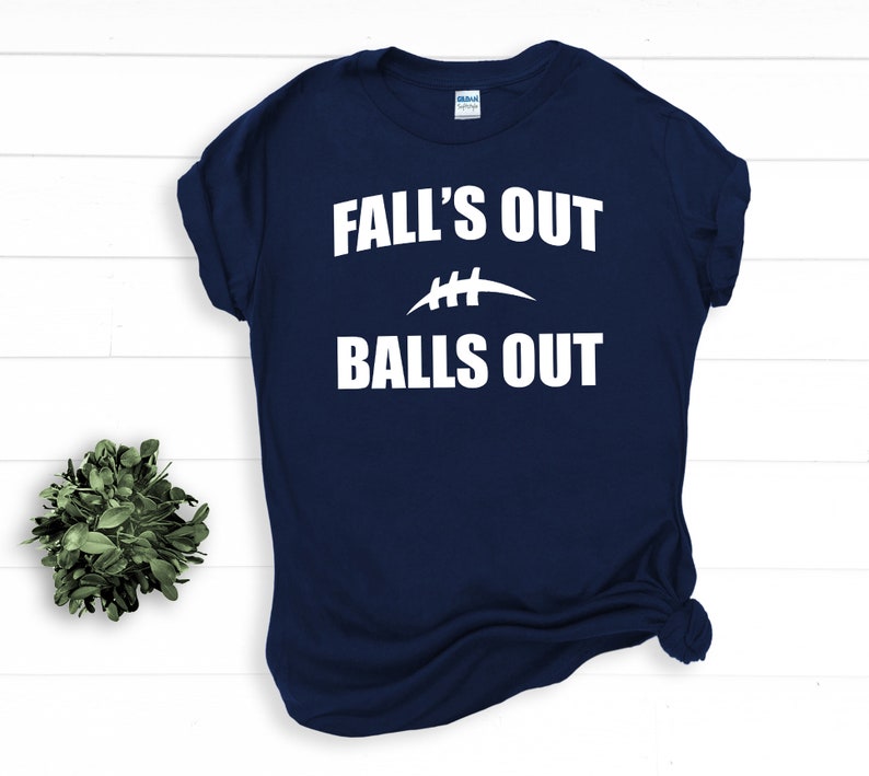 Puede incluir: Camiseta azul marino con texto blanco que dice "Fall's Out Balls Out" y un gr&aacute;fico de f&uacute;tbol blanco.