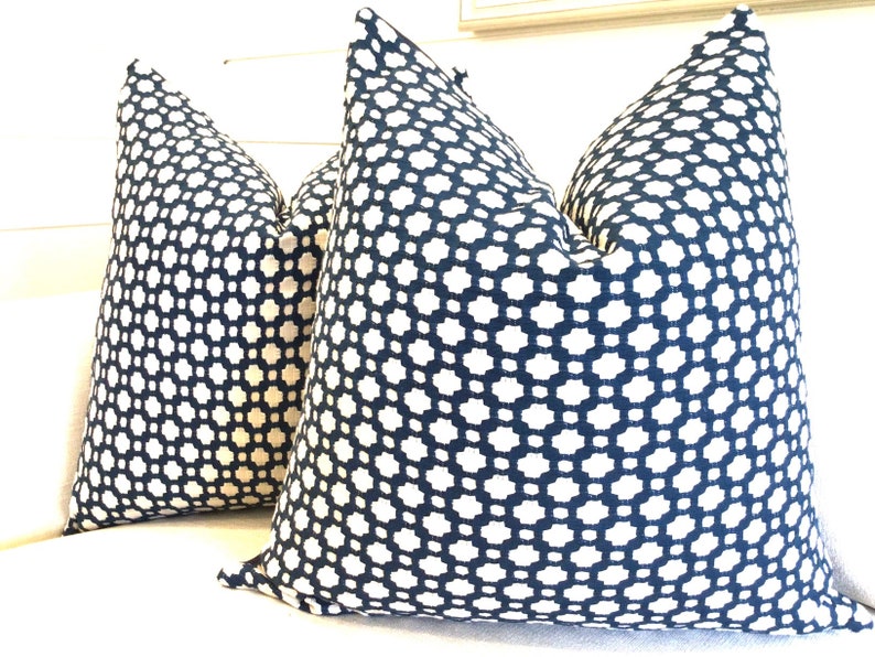 May include: Two navy blue throw pillows with a white geometric pattern. The pillows are made of a soft, textured fabric.
