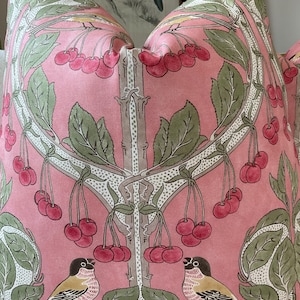 May include: Pink pillow with a floral pattern featuring cherry blossoms and birds. The pillow has a white background with green leaves and pink cherries.