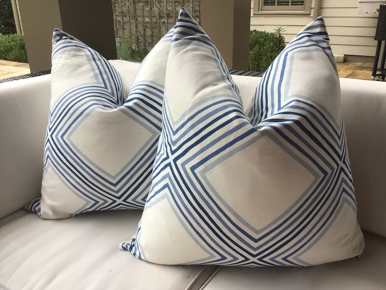 May include: Two white throw pillows with a blue and white geometric pattern. The pattern features diagonal lines and squares.