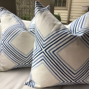 May include: Two white throw pillows with a blue and white geometric pattern. The pattern features a series of diagonal lines forming diamond shapes.