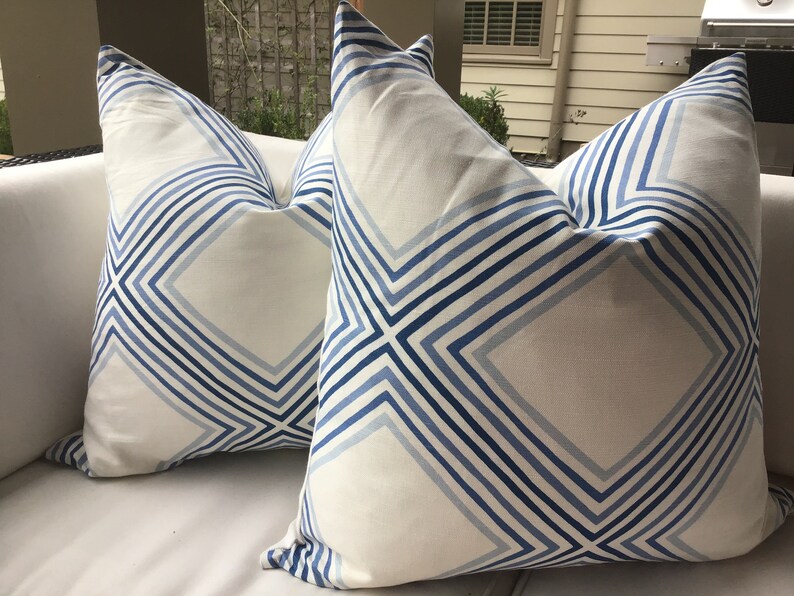 May include: Two white throw pillows with a blue and white geometric pattern. The pattern features a series of diagonal lines forming diamond shapes.