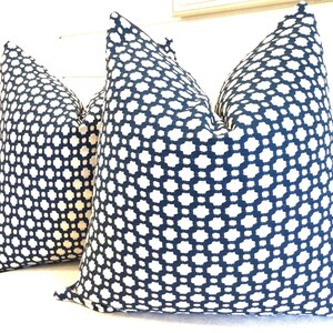 May include: Two blue and white patterned throw pillows with a geometric design. The pillows are made of a soft, woven fabric.