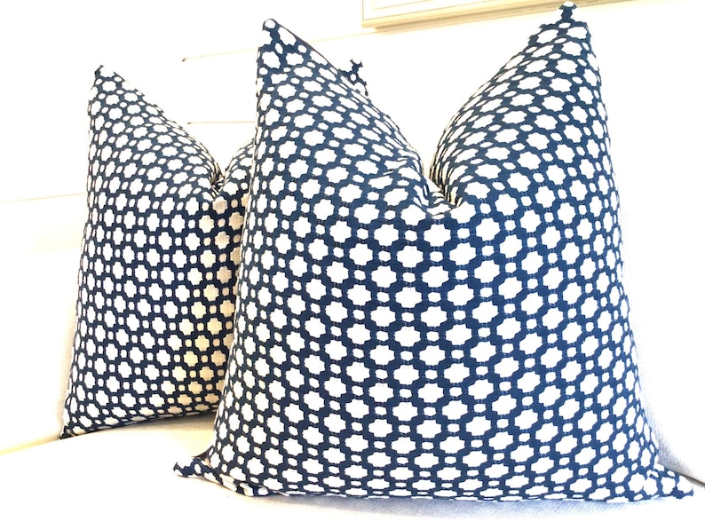 May include: Two blue and white patterned throw pillows with a geometric design. The pillows are made of a soft, woven fabric.