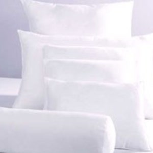 Puede incluir: Un conjunto de cinco almohadas blancas de diferentes tamaños. Las almohadas están apiladas, con la más grande en la parte inferior y la más pequeña en la parte superior.
