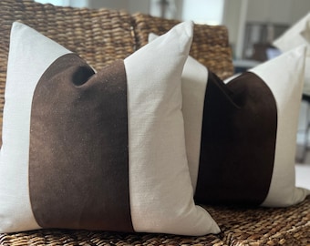 May include: Two brown and white striped throw pillows on a woven wicker chair. The pillows are made of a soft, textured fabric.
