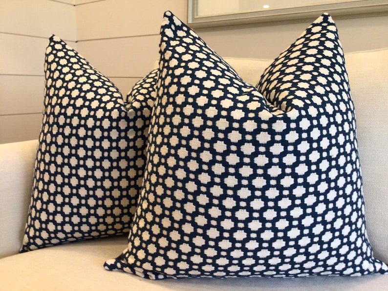 May include: Two decorative throw pillows with a geometric pattern. The pillows are navy blue with a white geometric pattern.