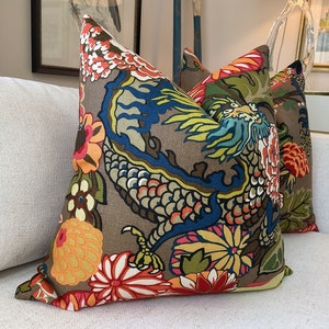 K&ouml;nnte beinhalten: Zwei dekorative Kissen mit braunem Hintergrund und einem bunten Drachen- und Blumenmuster.