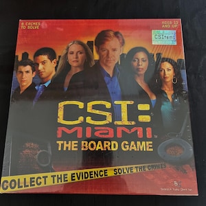 May include: A board game box featuring the cast of the TV show CSI: Miami. The box is red and black with the title "CSI: Miami The Board Game" in white letters. The text "Collect the Evidence Solve the Crimes" is printed in yellow on a black and yellow striped background.