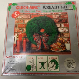 以下が含まれることがあります： クイック・マックのリースキットの箱。緑のリースに赤と白のチェック柄のリボン、キャンドル、クッキーの皿が飾られています。箱には「マクラメを簡単に作る新しい方法」と「アメリカ製」と書かれています。