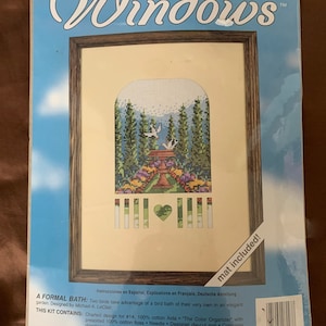 May include: A counted cross stitch kit titled "Windows" featuring a bird bath with two birds in a garden setting. The kit includes 100% cotton Aida fabric, presorted floss, a needle, a designer die-cut mat, and complete instructions. The finished size is 5 7/8 inches by 7 1/2 inches (13 cm by 20 cm).