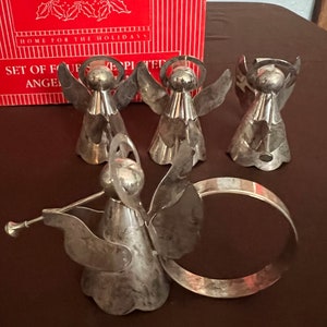 Puede incluir: Conjunto de cinco anillos de servilleta de &aacute;ngel de plata. Los &aacute;ngeles sostienen trompetas y tienen halos. Los anillos est&aacute;n en una caja que dice "Home for the Holidays" y "Set of Four Silver Plated Angel Napkin Rings".
