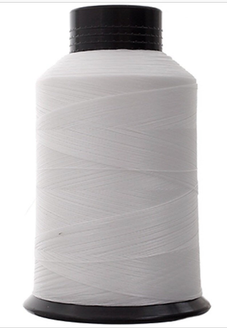 May include: A white spool of thread with a black plastic top and bottom.