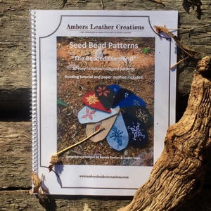 May include: A spiral bound book titled "Ambers Leather Creations" with the words "Seed Bead Patterns" and "The Beaded Diamond" on the cover. The book features 10 easy to follow coloured patterns for beading, with a beading tutorial and paper method included. The cover also includes a photo of several colourful beaded diamond shapes.