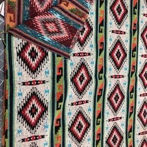 May include: A close-up of a fabric with a Southwestern-inspired pattern. The fabric features a repeating design of diamonds, stripes, and geometric shapes in shades of red, black, green, blue, and white.