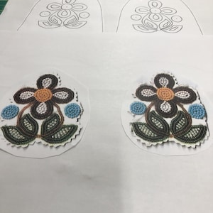 May include: Two white paper templates with black outlines of a flower design. Below the templates are two beaded flower designs with brown, white, blue, and orange beads.