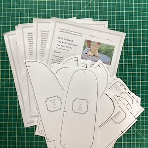 Puede incluir: Un conjunto de patrones de papel blanco para hacer mocasines. Los patrones incluyen instrucciones para cortar las piezas del pie, la pala y la envoltura. Las instrucciones incluyen el texto "Cómo hacer el área del mocasín para tus envolturas".