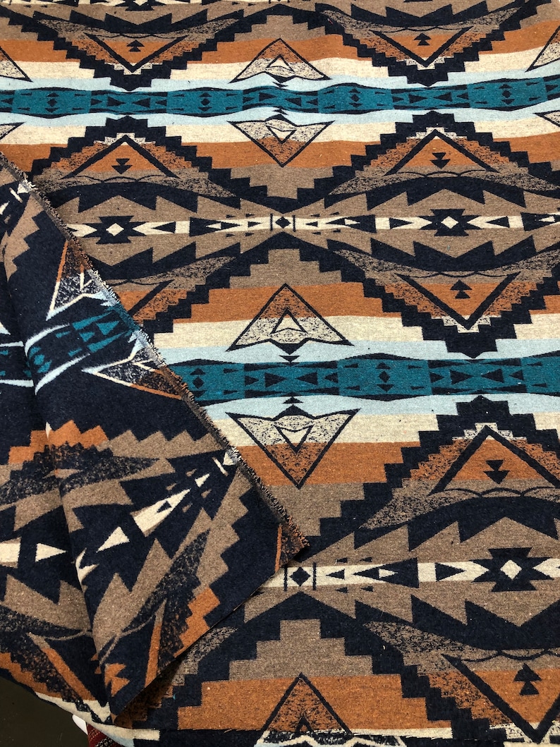 May include: A close-up of a woven fabric with a geometric pattern in shades of brown, teal, and white. The fabric has a textured surface and a slightly fuzzy appearance.