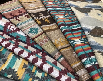 May include: A collection of six colourful woven blankets with geometric patterns in shades of brown, teal, red, and white. The blankets are folded and arranged in a fan shape.